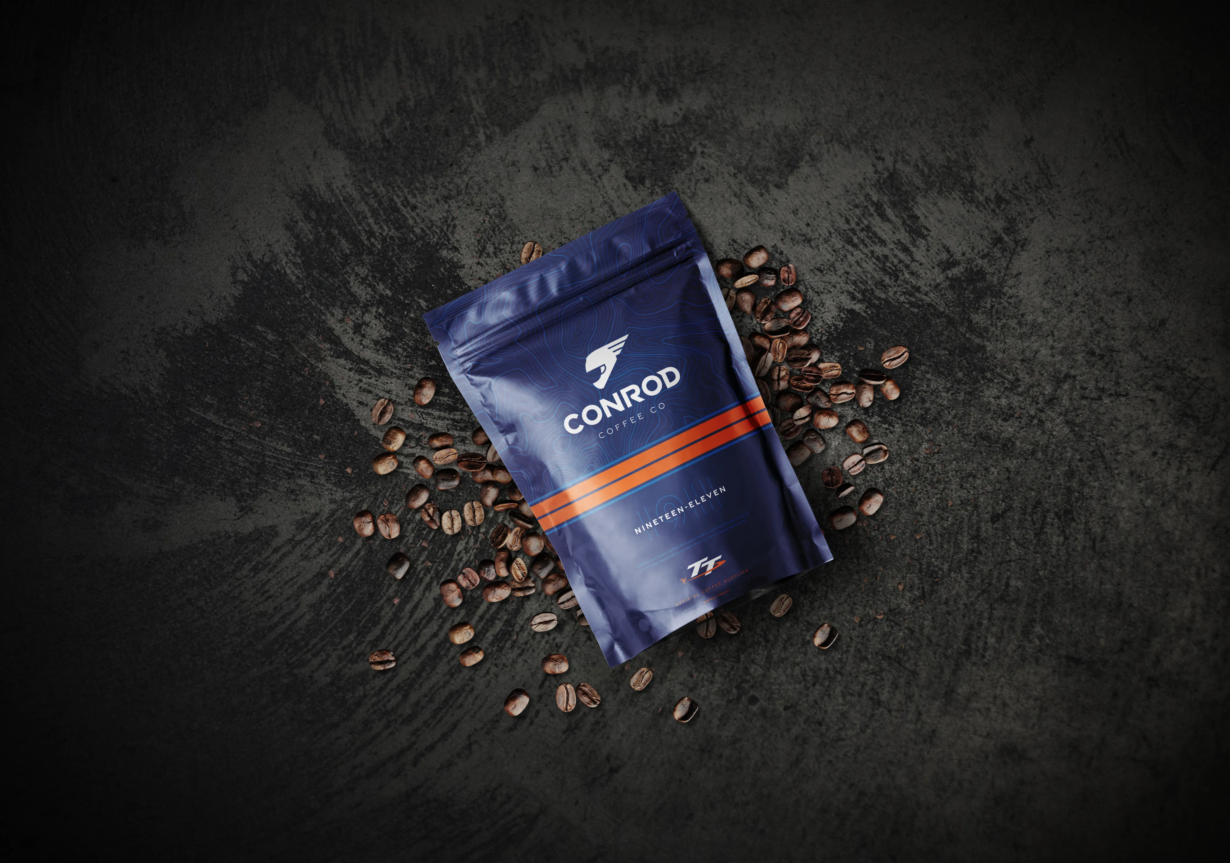 Blue coffee bag labeled "Conrod Coffee Co" on dark textured background surrounded by scattered coffee beans. Elegant and sophisticated branding.